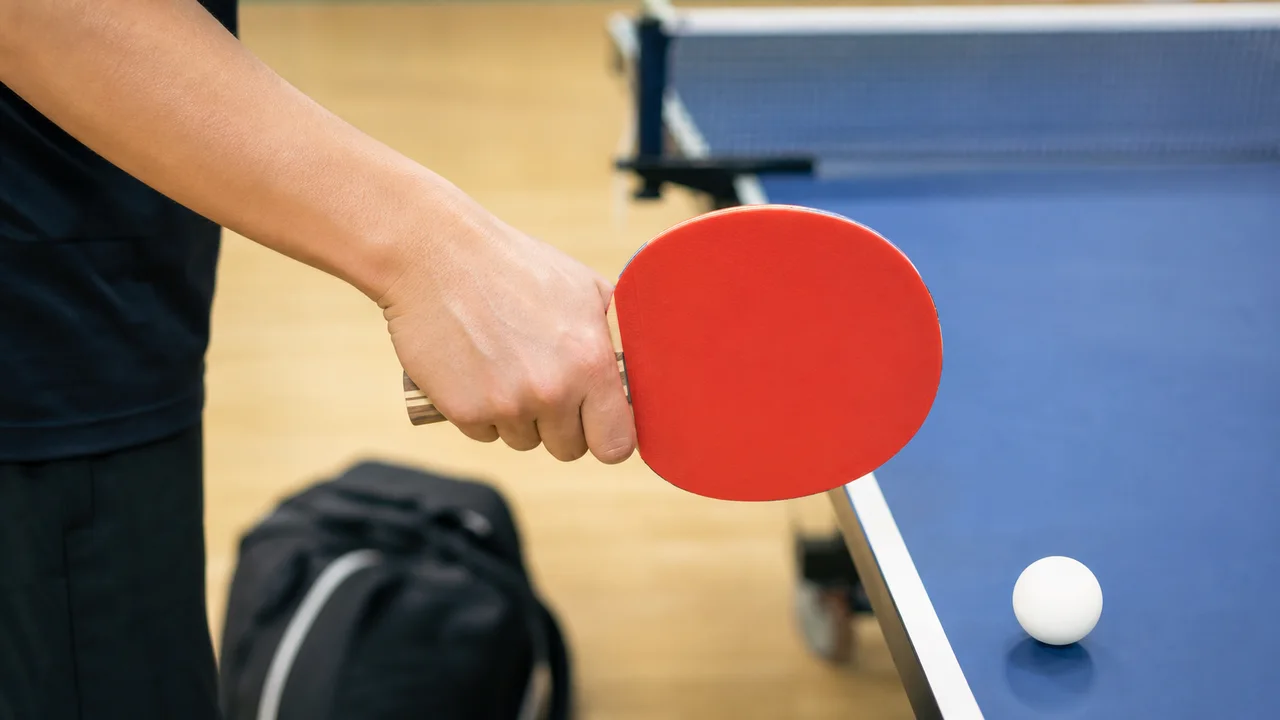 Main tenant une raquette de ping-pong pres de la table